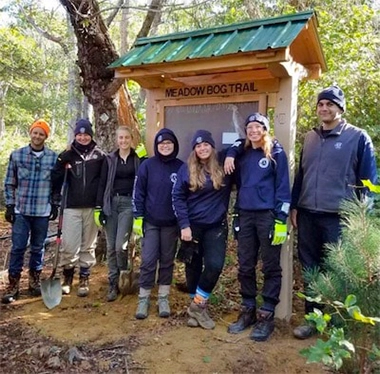 Group standing beside a trail information sign