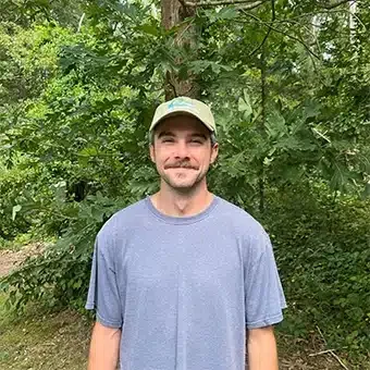 Smiling man standing in a wooded area