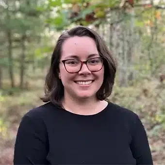 Smiling woman wearing glasses in a wooded area