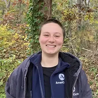 Smiling person standing in a wooded area